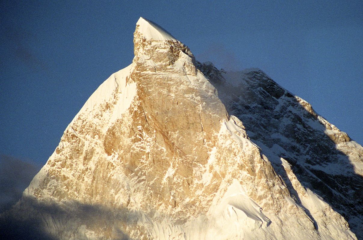 15 Masherbrum Close Up At Sunrise From Goro II The next morning dawned clear with the first rays of the sun hitting Masherbrum with its ice cream cone top glistening in the sun from Goro II. The summit of Masherbrum's sheer north face is a perfect pyramid, with steep narrow ridges rising suddenly to a sharp pinnacle.  It was first climbed via the south west face on July 6, 1960 by George Bell and Willi Unsoeld on an American - Pakistani expedition. Two few days later on July 8, expedition leader Nick Clinch and Pakistani Captain Jawed Akhter Khan also reached the summit.
